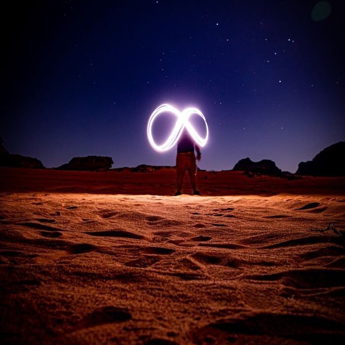 A man light painting under a starry sky in Wadi Rum desert, capturing the beauty of the night.