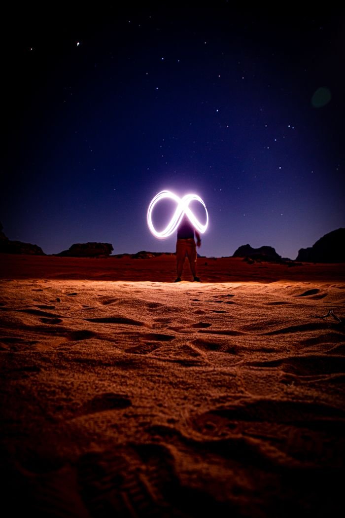 A man light painting under a starry sky in Wadi Rum desert, capturing the beauty of the night.